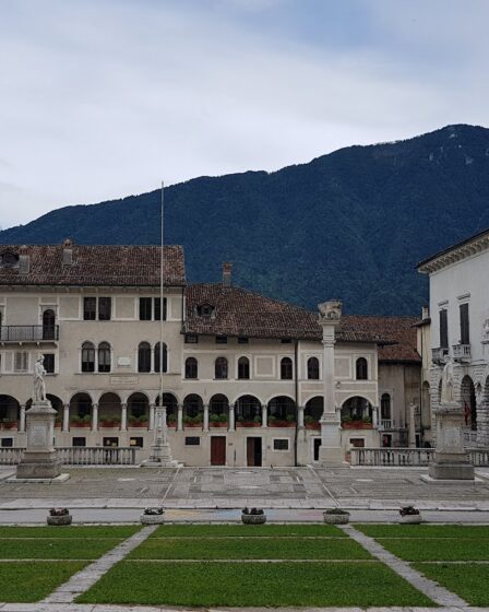 Piazza Maggiore a Feltre, con i palazzi, i portici, le fontane e le montagne sullo sfondo