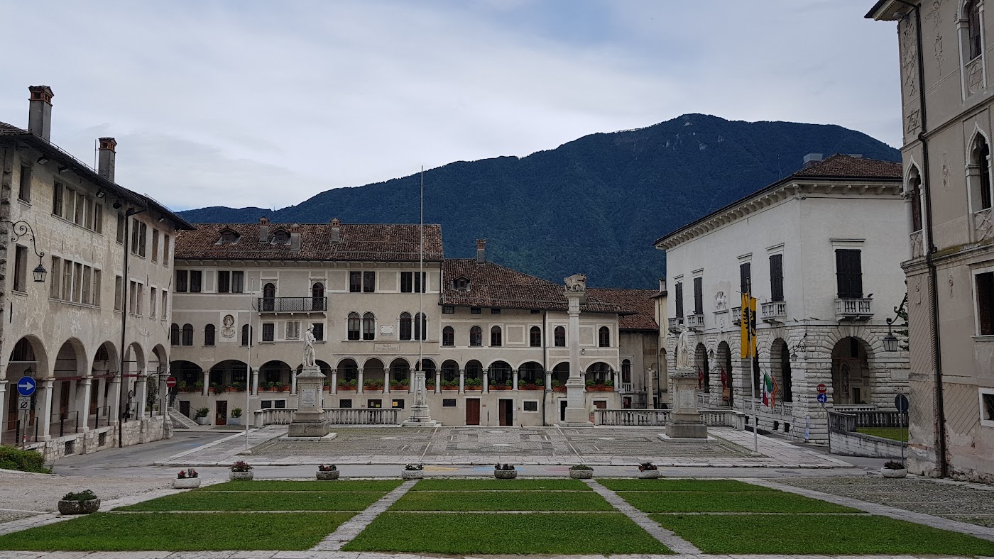 Piazza Maggiore a Feltre, con i palazzi, i portici, le fontane e le montagne sullo sfondo